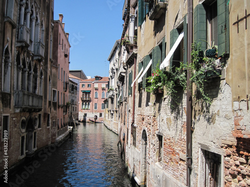 Scenic Venetian cityscape with narrow canal on a sunny summer day.