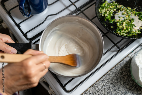 Tableau sur toile Woman cooking bechamel sauce at home. Close up.