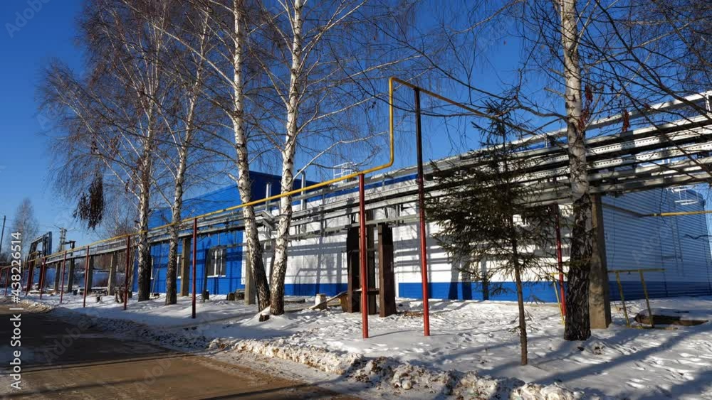 Contemporary workshop building with pipeline and birches at contemporary waste water treatment plant on winter day Contemporary workshop building with pipeline and birches at contemporary waste water treatment plant on winter day