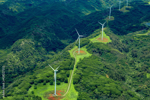 Aerial photo of white windmills in a line on green land leading off into the horizon. photo