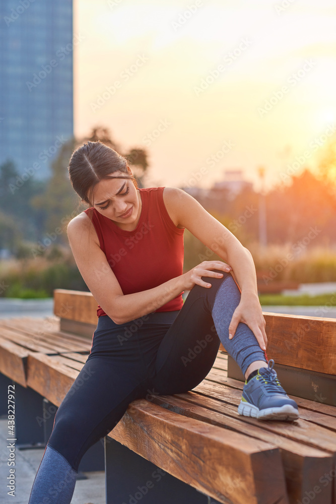 Young sportswoman having pain injury during exercise and jogging in the park..