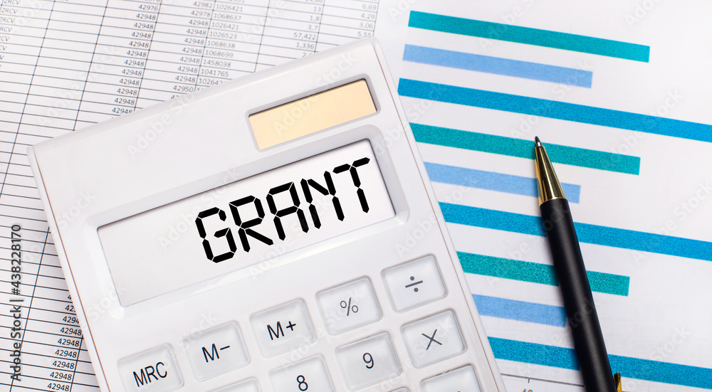 Against the background of reports and blue graphs, a pen and a white calculator with a test on the GRANT screen. Business concept