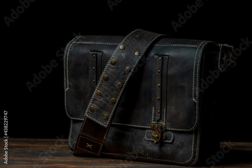 Retro style dark leather messenger bag with rivet straps.
