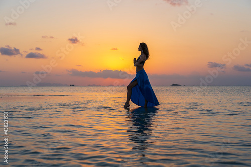 Young beauty girl dancing at tropical beach on sea water at paradise island at sunset. Summer concept © OlegD