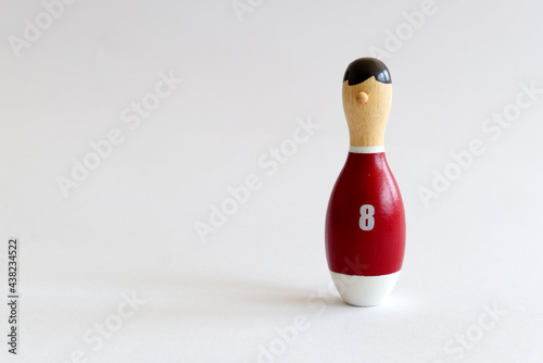 rearview of a wooden puppet in the shape of a bowling pin with a number eight shirt