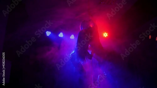 Two women dancing around the pole by the light of colorful lights. Pole dance.