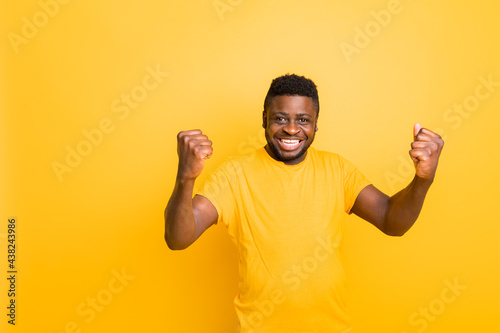 Excited overjoyed young triumphant male, winner looking at camera, celebrate bet bid win online success victory, isolated on yellow studio background, excited black guy winner rejoicing victory