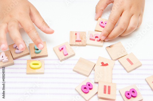 Child plays with wooden numbers, makes a chain of cisels, simple children's math activities