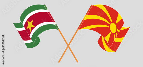 Crossed and waving flags of Suriname and North Macedonia
