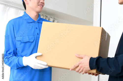 作業服を着た男性が荷物を渡すイメージ