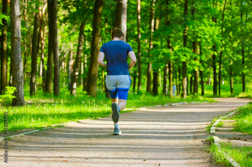 A sporty fitness man jogging in a park on a sunny spring summer day. Lifestyle.