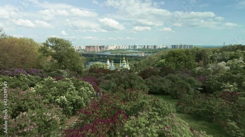 Aerial view of blooming botanical garden overlooking church and slopes of Dnieper