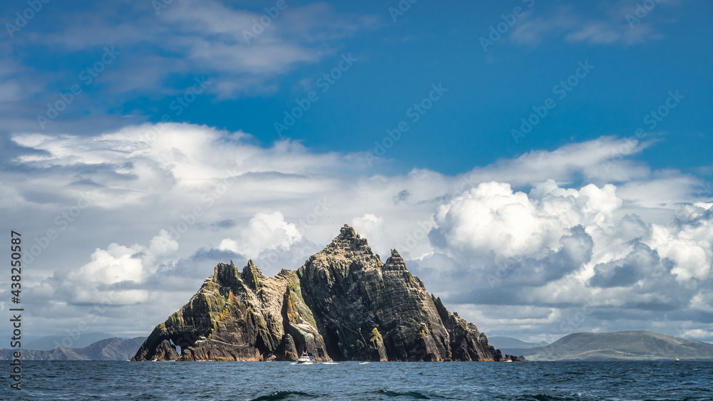 Cruise boat in front of Little Skellig island, habitat of Gannets, Morus Bassanus, with Irish coastline in the background, Ring of Kerry, Ireland
