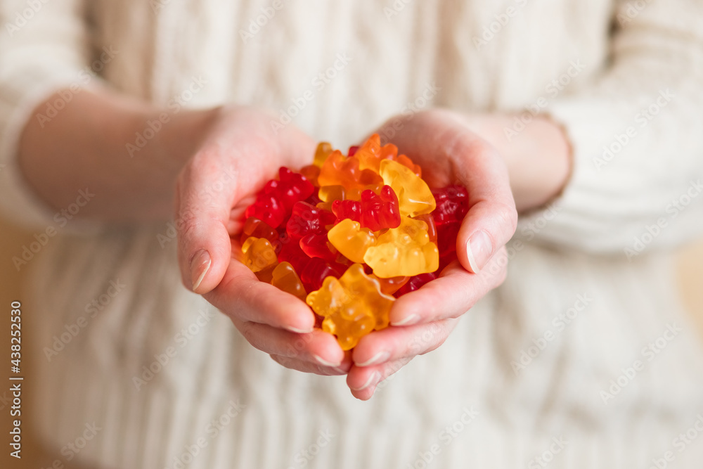 Close-up image of a woman holding multi-colored gummy bears. Close-up image of a woman holding multi-colored gummy bears.