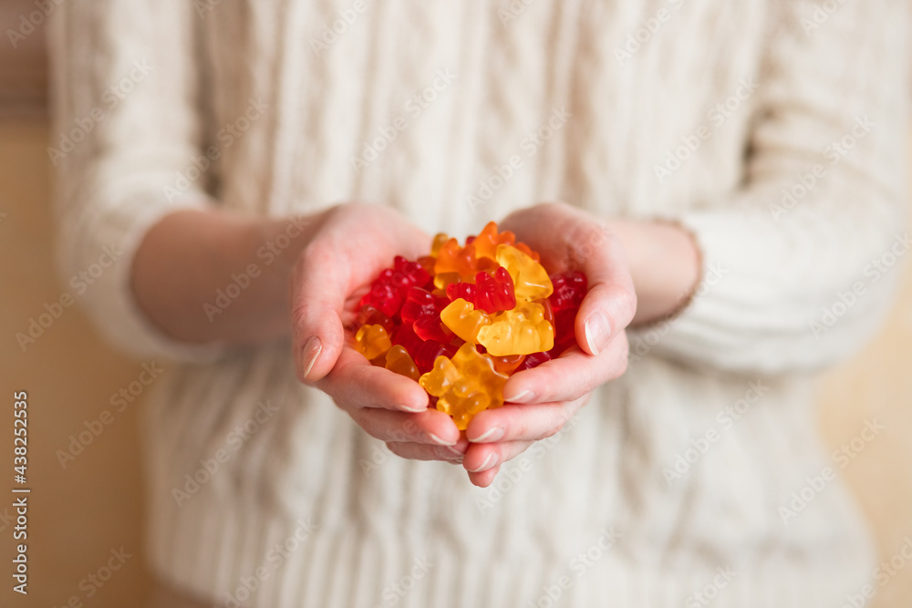 Close-up image of a woman holding multi-colored gummy bears. Close-up image of a woman holding multi-colored gummy bears.
