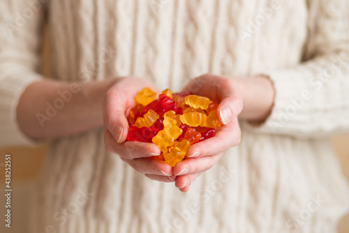 Close-up image of a woman holding multi-colored gummy bears.