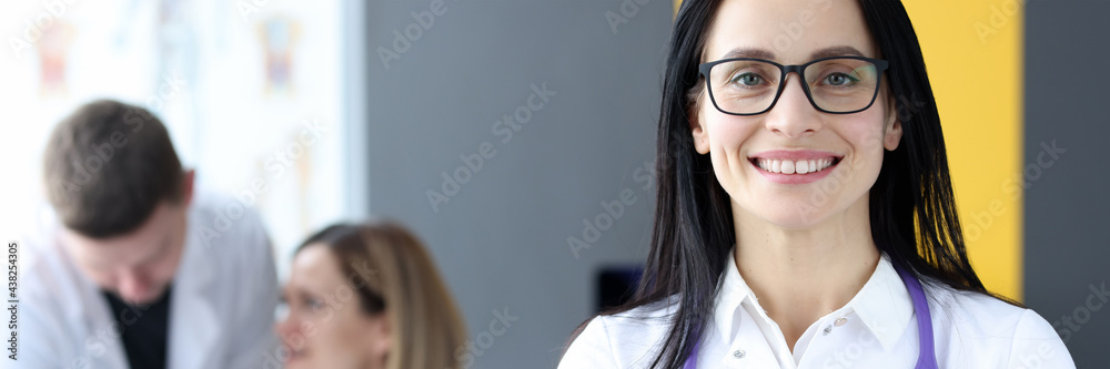 Portrait of smiling female doctor on background of colleagues Portrait of smiling female doctor on background of colleagues