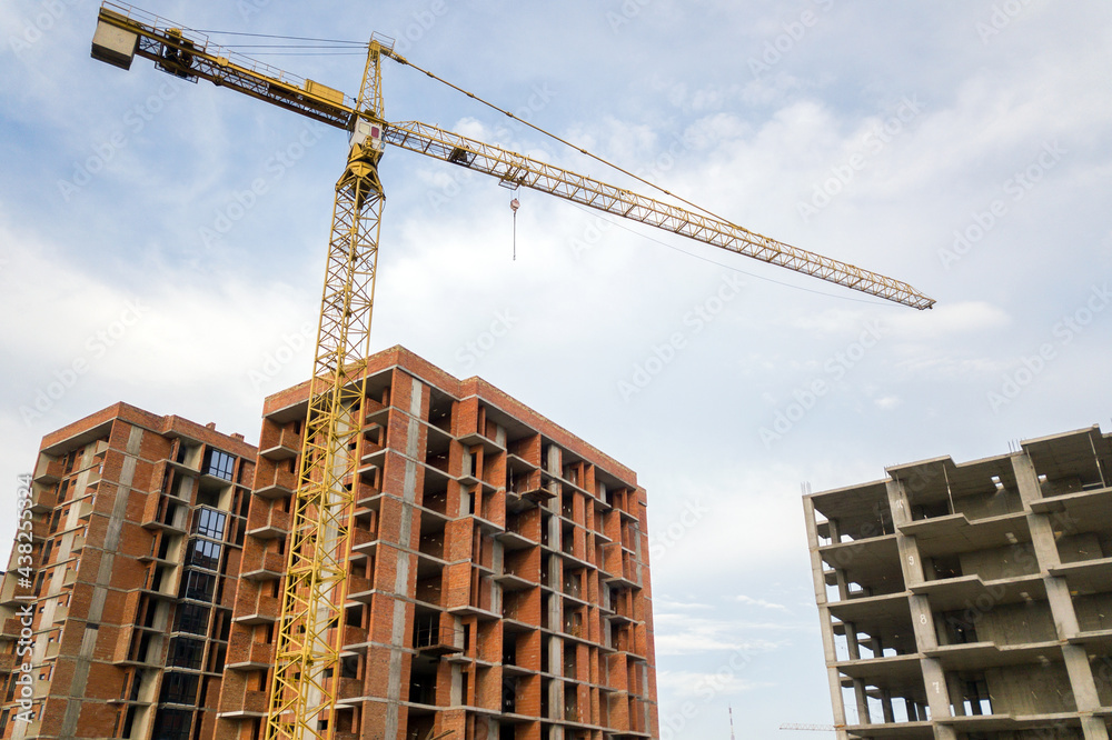 High-rise residential apartment buildings and tower crane under development on construction site. Real estate development.