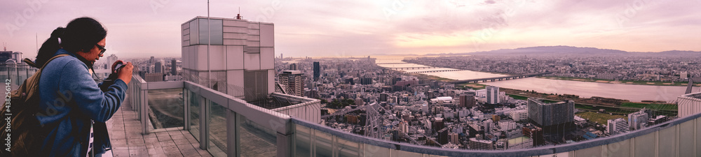 Amazing super wide panorama view of the Osaka skyline from the Umeda Sky Building in in the afternoon with traveler taking pictures, Osaka, Japan