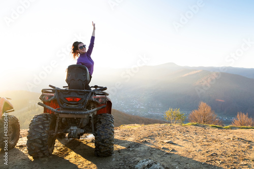 Happy female driver enjoying offroad riding on ATV quad motorbike in autumn mountains at sunset.