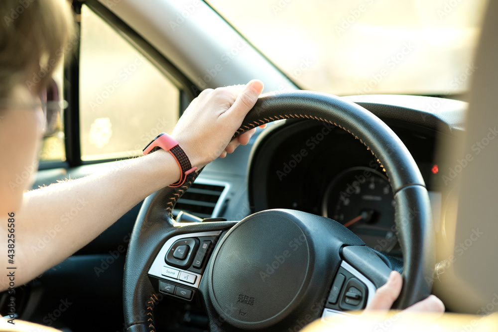 Close up view of woman holding steering wheel driving a car on city street on sunny day. Close up view of woman holding steering wheel driving a car on city street on sunny day.