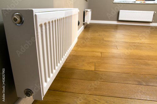 White metal heating radiator mounted on gray wall inside a room.