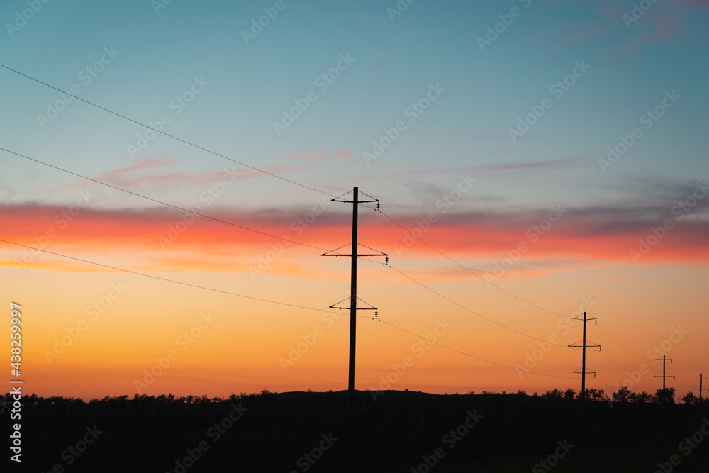 Poles with wires at sunset, in the evening.