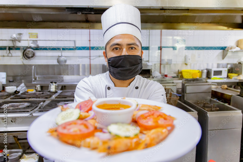 Portrait of Mexican Chef presenting plate in kitchen Portrait of Mexican Chef presenting plate in kitchen