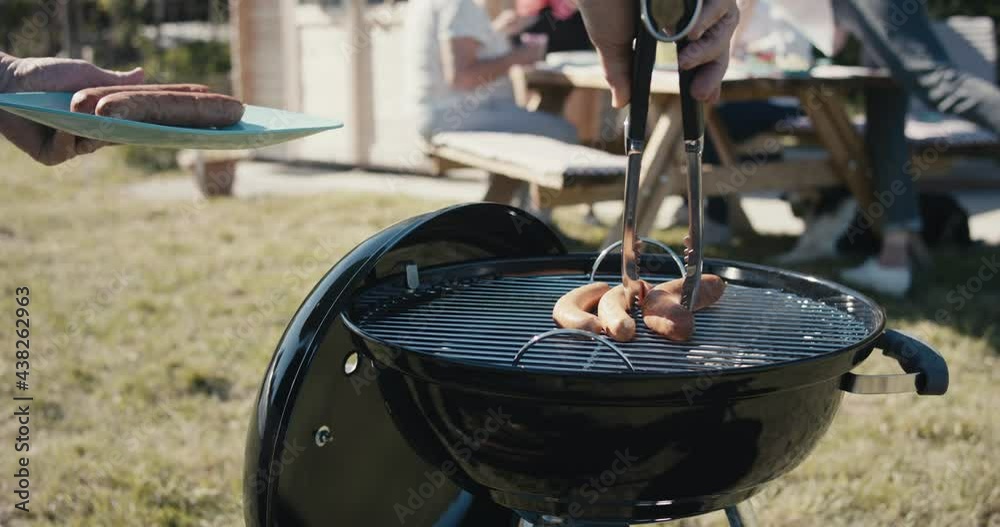 Senior man grill sausage meat food tongs in hand bbq picnic close up Senior man grill sausage meat food tongs in hand bbq picnic close up