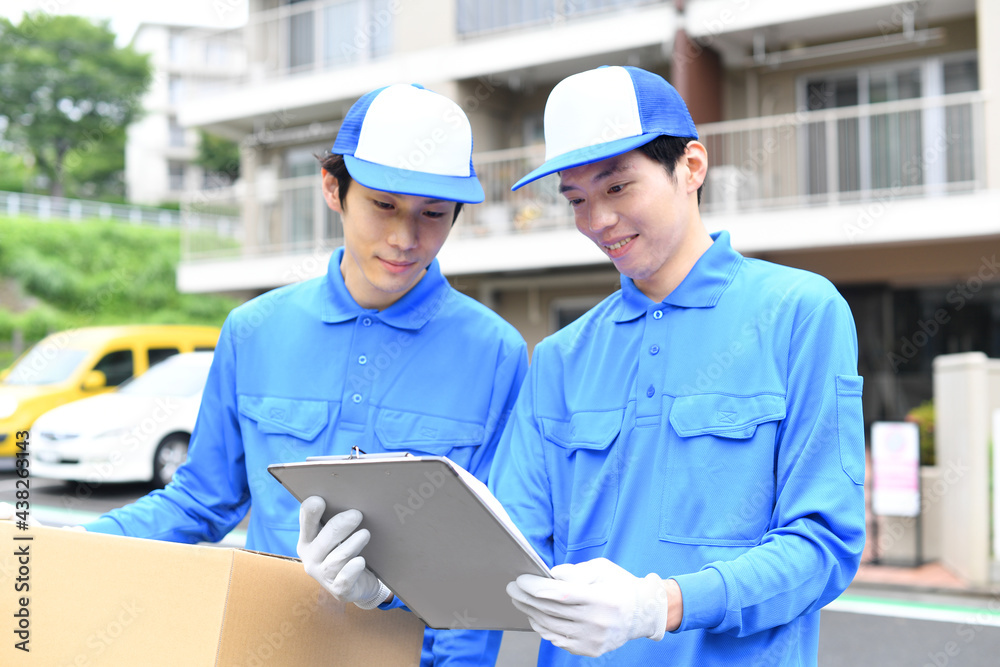 屋外で作業服を着た複数の男性が引っ越しの段ボールを運ぶイメージ 屋外で作業服を着た複数の男性が引っ越しの段ボールを運ぶイメージ