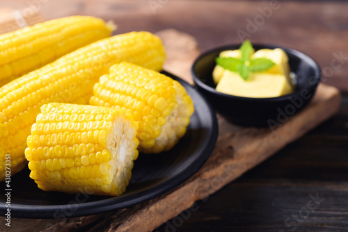 Sweetcorn cob and butter in a bowl on wooden background