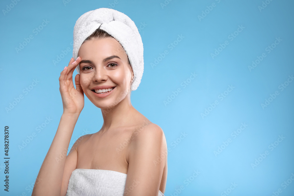 Happy young woman with towel on head against light blue background, space for text. Washing hair Happy young woman with towel on head against light blue background, space for text. Washing hair