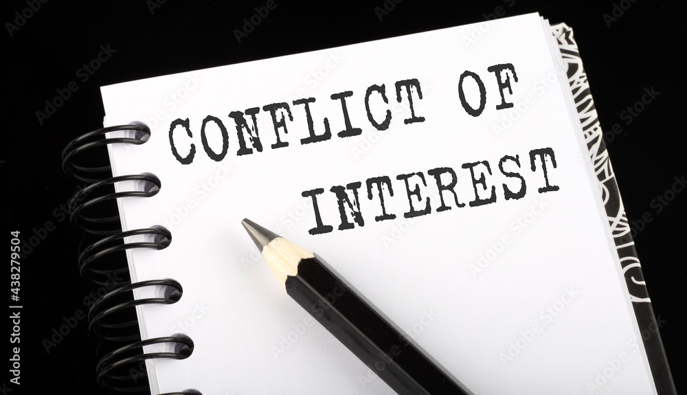 CONFLICT OF INTEREST written text in small notebook on a black background