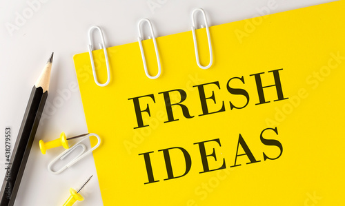 FRESH IDEAS word on the yellow paper with office tools on white background