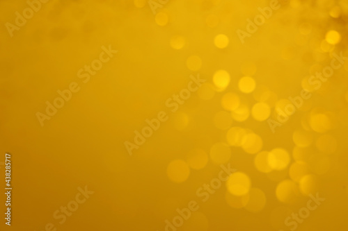 Blurred view of golden lights on yellow background, space for text. Bokeh effect