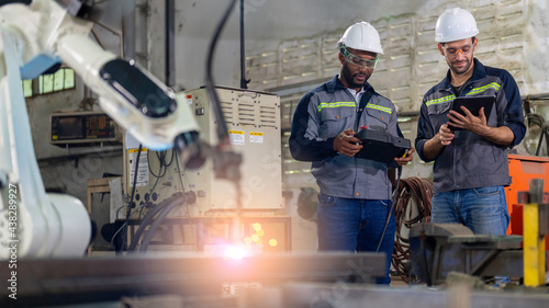 Two Industry engineers stand and discussion work in the factory workshop.