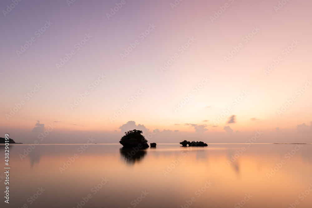 Gorgeous long exposure sunset. Smooth sea surface, islets in silhouette, pastel colors sky mirrored on the ocean. Iriomote Island.