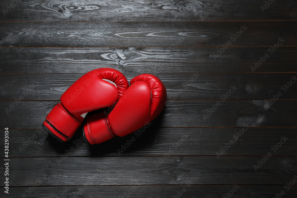 Pair of red boxing gloves on dark wooden background, flat lay. Space for text
