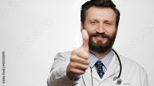 Doctor thumb up. Portrait of positive smiling man doctor on white background looking at camera and shows his thumb up