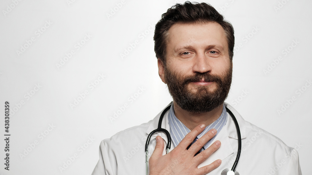 Doctor respect bow. Smiling man doctor on white background looking at camera and puts his hand on chest and bows, expressing respect or greeting Doctor respect bow. Smiling man doctor on white background looking at camera and puts his hand on chest and bows, expressing respect or greeting