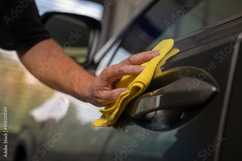detail of hand wiping door of a car with cloth photo