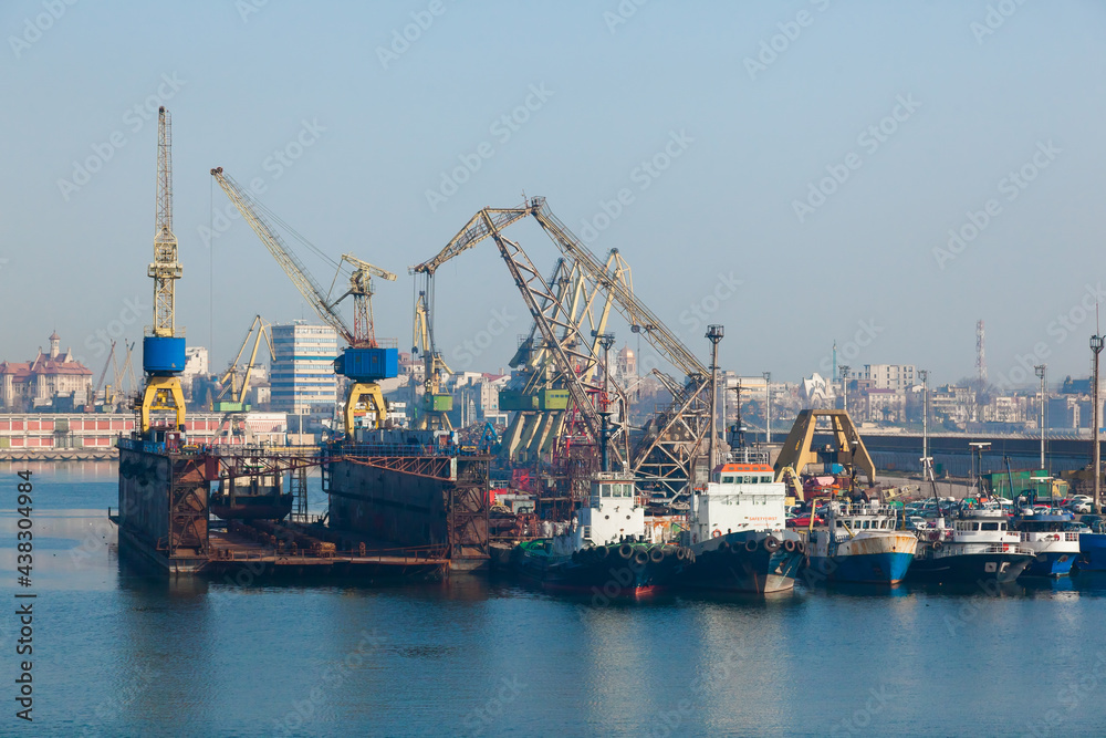 Seaport in Constanta Romania. Marine tugs at berth, harbor cranes and dry dock.