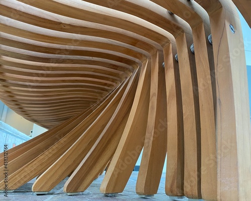 Looking up at the backside of a wood carved bench made of planks of beige wood