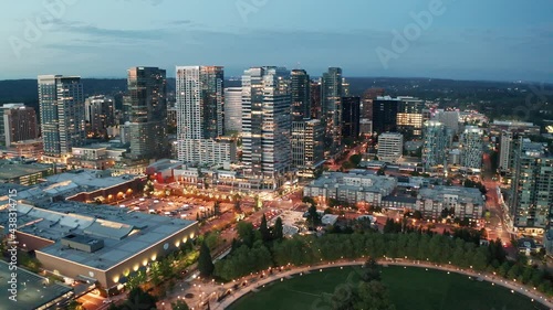 Cinematic trucking 4K aerial drone night shot of the city center of Bellevue, Downtown Park, Bellevue Square, illuminated skyscrapers, tall office and apartment buildings during blue hour after sunset photo