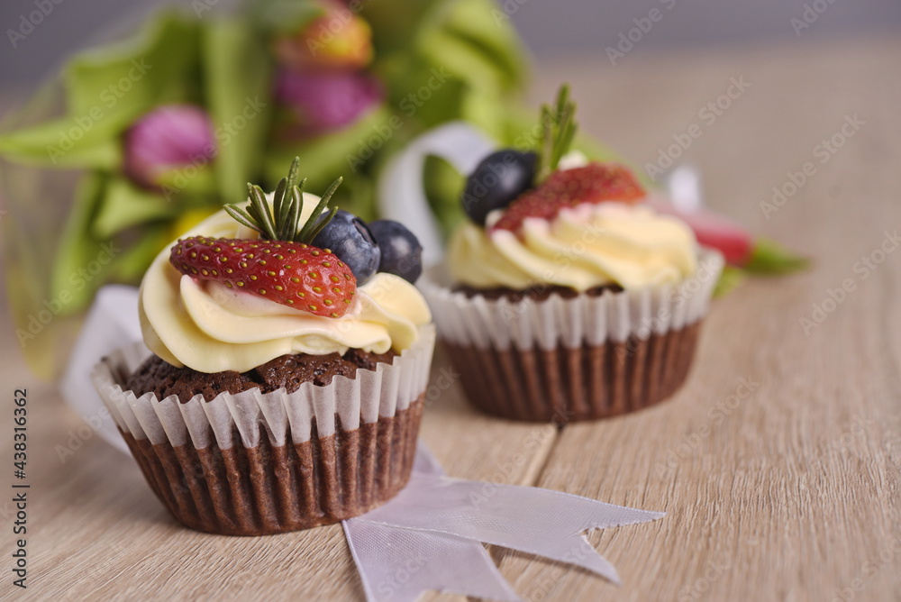 Cupcakes with berries and greeting flowers are laid out on the table.