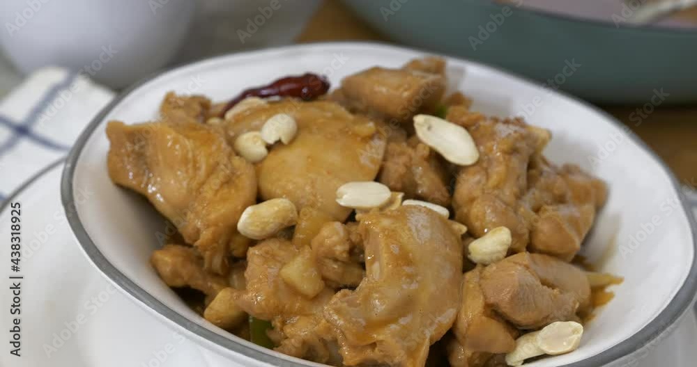 Sprinkling peanuts onto a bowl of homemade Kung Pao Chicken close up Sprinkling peanuts onto a bowl of homemade Kung Pao Chicken close up