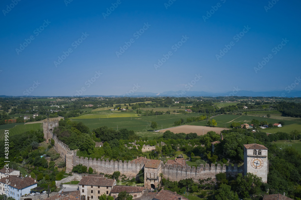 Monzambano Castle, Italy. Old clock on the tower of the castle. Aerial view of the Italian historic castle Castello di Monzambano on the hill.