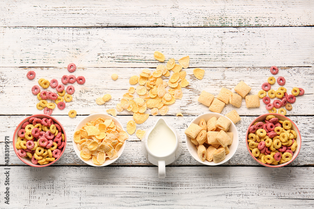 Composition with different cereals and milk on light wooden background