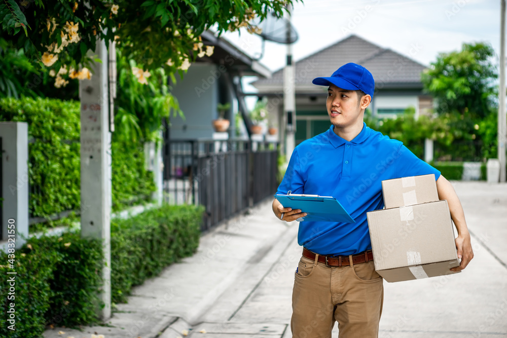 A young Asian deliveryman is delivering parcel to customer house ordered online during the outbreak of the coronavirus or Covid-19 virus.