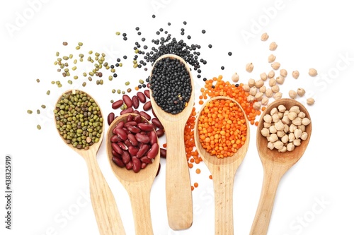 Spoons with different legumes on white background